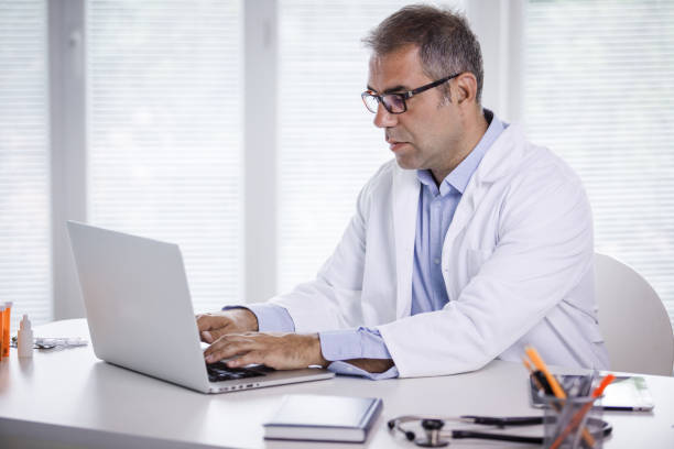 istock Doctor using his laptop to pull out patients medical record 1210167313