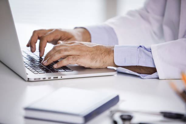 Keeping track of patients medical records using computer technology Cut out of a male doctor's hands using a laptop to enter lab results of a patient in the system of the hospital. entering data stock pictures, royalty-free photos & images