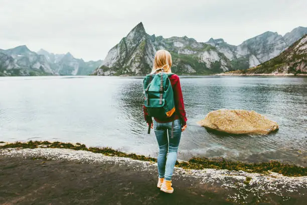 Traveler woman walking at fjord Lofoten islands in Norway Travel lifestyle concept summer vacations outdoor scandinavian nature