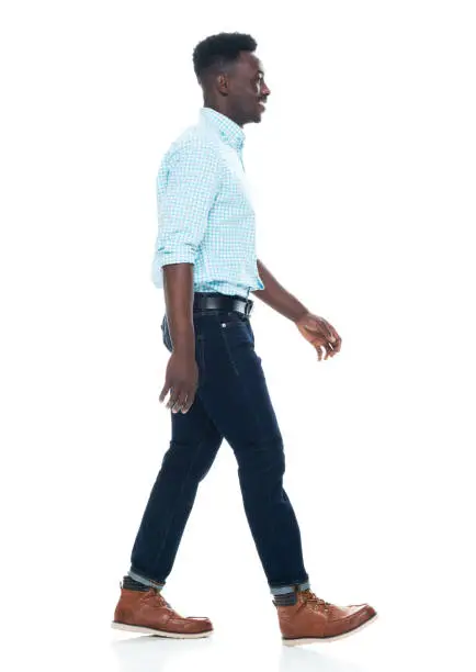 Photo of African ethnicity male walking in front of white background wearing jeans