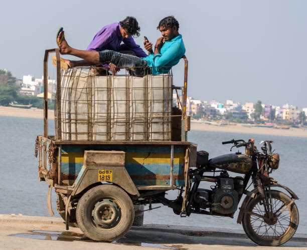 Diu #29 Diu, India - December 2018: Two fishermen relax on top of ice boxes loaded on a three wheeler vehicle by a pier on the island of Diu. diu island stock pictures, royalty-free photos & images