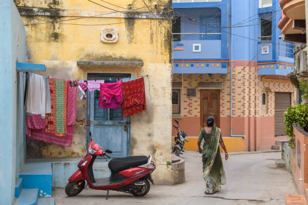 Woman walking on a narrow street in a residential part of Diu Diu, India - December 2018: Back profile of a woman who walks past a clothesline with drying clothes in the narrow lanes of a residential district in the island of Diu. diu island stock pictures, royalty-free photos & images