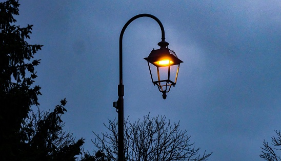 Typical street lamps in a historic Algarve town in Portugal. View from below against a pale blue sky.