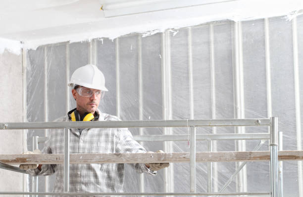 istock man work, professional construction worker  with scaffolding, safety hard hat, hearing protection headphones, gloves and protective glasses. on interior building site, copy space background 1210176753