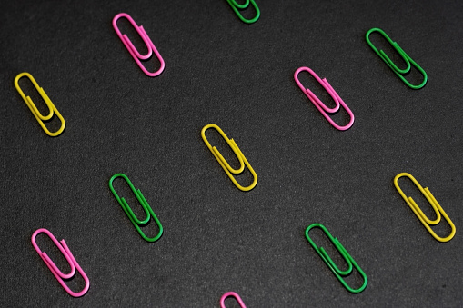 multicolored paper clips on a black background