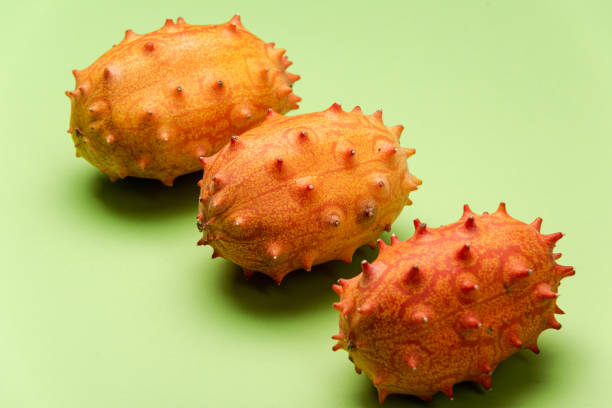 kiwano oder gehörnte melone auf grünem pastell hintergrund. exotische früchte - kawani fruit stock-fotos und bilder