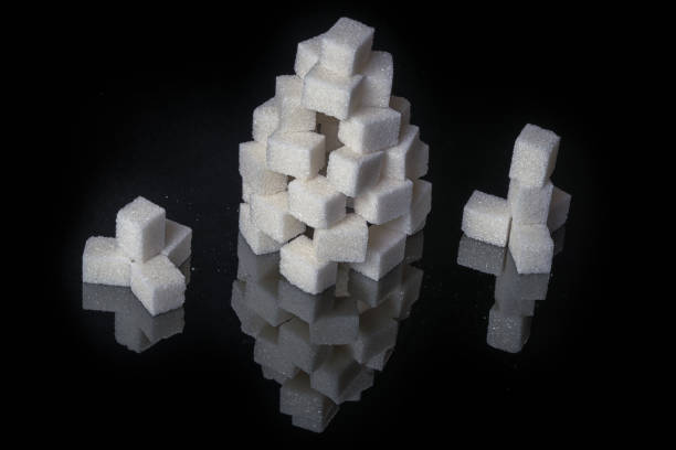 Sugar towers on a black mirror surface with reflections isolated on black background. Red light behind some.