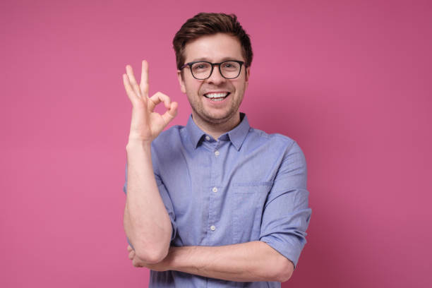 istock Smiling young man with glasses smiling shows Ok symbol 1210180473