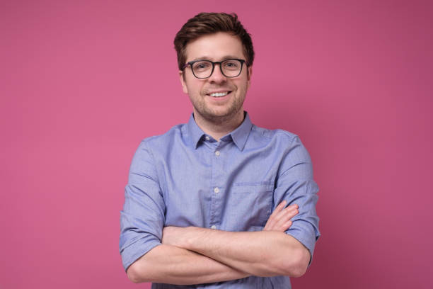 istock Smiling young man with glasses standing with arms crossed 1210182220
