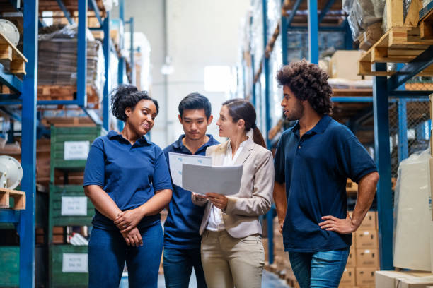 Female manager discussing delivery schedules with staff Female manager discussing delivery schedules with staff in warehouse. Female supervisor talking with employees in warehouse. foreman stock pictures, royalty-free photos & images