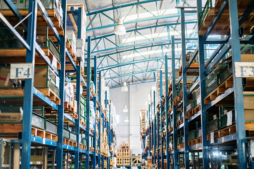Interior of a large distribution warehouse. Rows of big racks and shelves in factory storage room.