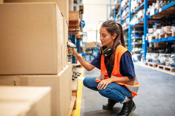 Female worker scanning boxes in warehouse rack Warehouse worker crouching down and checking boxes on shelves with scanner. Female worker scanning boxes in rack. warehouse stock pictures, royalty-free photos & images