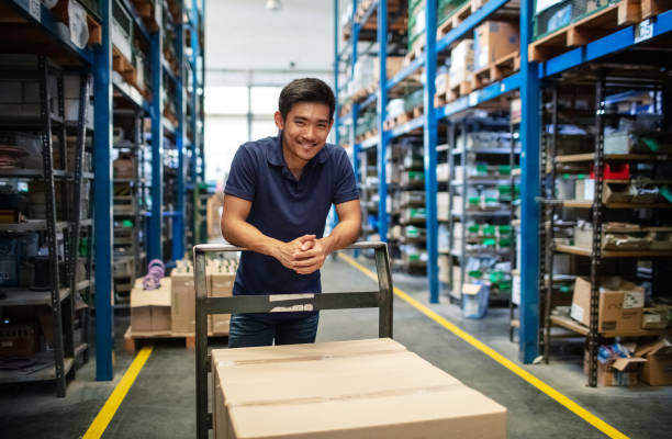Warehouse worker with a trolley in aisle
