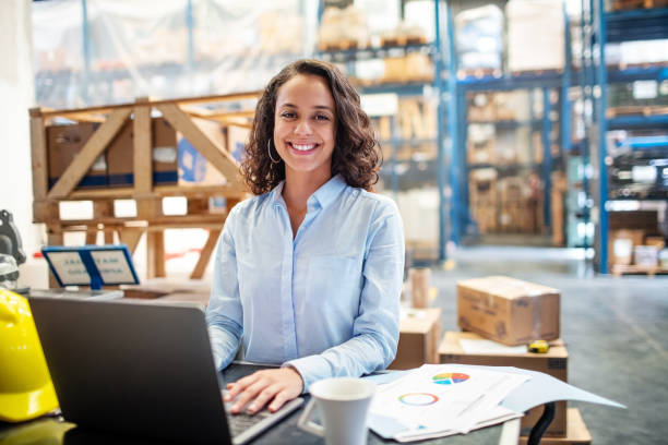 una empresaria con una laptop trabajando en el almacén - warehouse manager place of work portrait fotografías e imágenes de stock