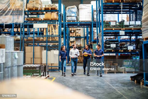 Warehouse Employees Walking Through Aisle And Talking Stock Photo - Download Image Now