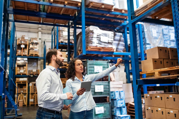 Manager and supervisor taking inventory in warehouse Businesswoman with a digital tablet showing and talking with male worker in distribution warehouse. Manager working with foreman in warehouse checking stock levels. delivering stock pictures, royalty-free photos & images