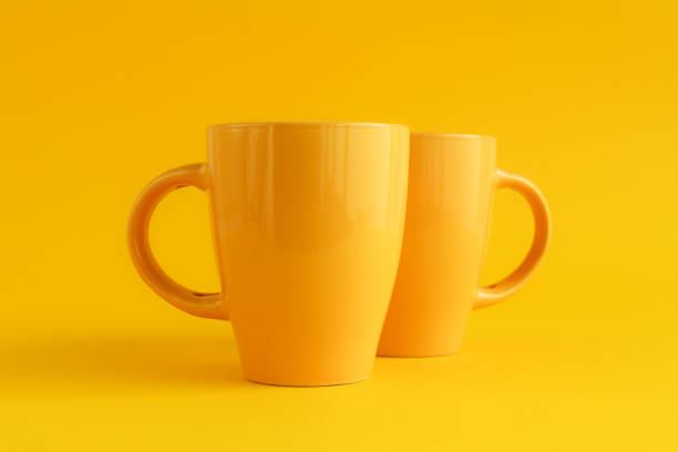 istock Two yellow coffee cups on yellow background 1210182464