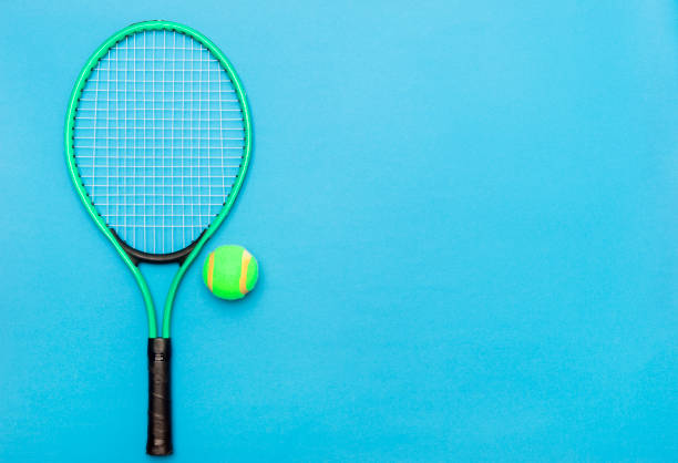 青い背景にテニスボールとラケット。スポーツ用品。フラットレイ。 - tennis court action toughness ストックフォトと画像