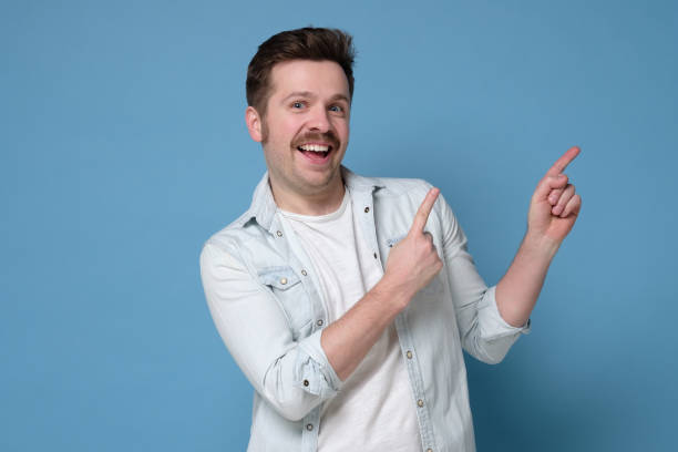 istock Handsome young man with funny mustache showing aside on copyspace. 1210185422