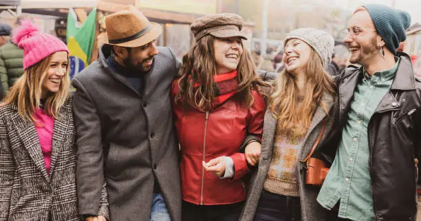 Photo of Millennial hipsters walking on the street of London - Friendship and freedom concept - Happy multiethnic friends walking in town and celebrating - Desaturated Filter - Focus on Hats. Fun Together