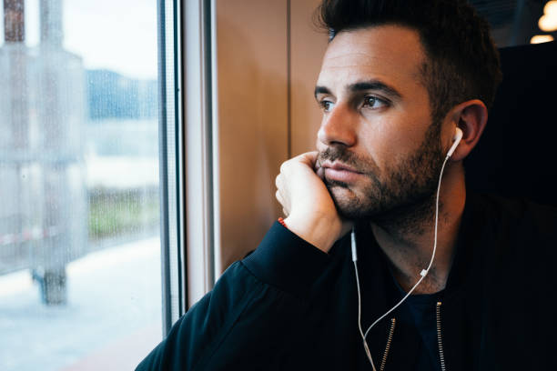 istock Young man traveling by train wearing earphones 1210189832
