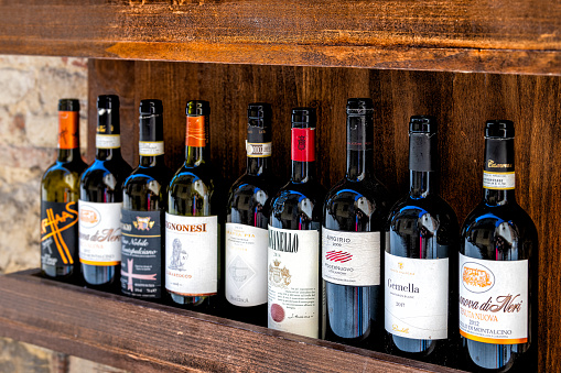 Montepulciano, Italy - August 28, 2018: Row of red wine bottle of Argirio, Avignonesi and Gemella on store shop display in Tuscan town or city of Tuscany