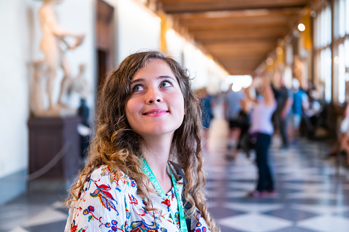 Firenze, Italy - August 30, 2018: People person tourist young woman happy face closeup on tour looking up at famous Florence Uffizi museum
