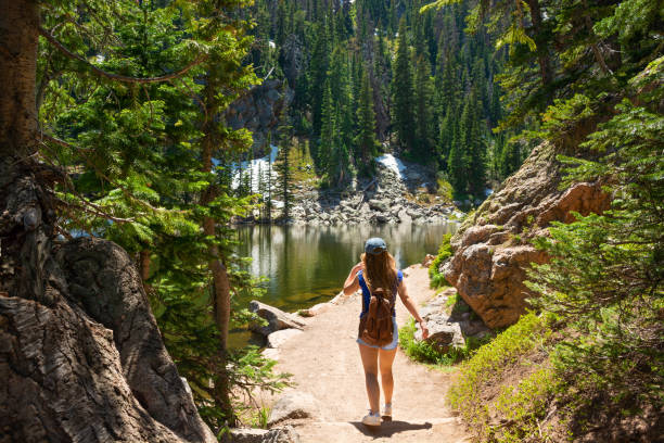 Woman hiking  in Colorado mountains. Girl exploring Colorado mountains on summer vacation hiking trip. Woman hiking alone on Emerald Lake Trail next to Dream Lake. Estes Park, Rocky Mountains National Park,Colorado,USA. estes park stock pictures, royalty-free photos & images