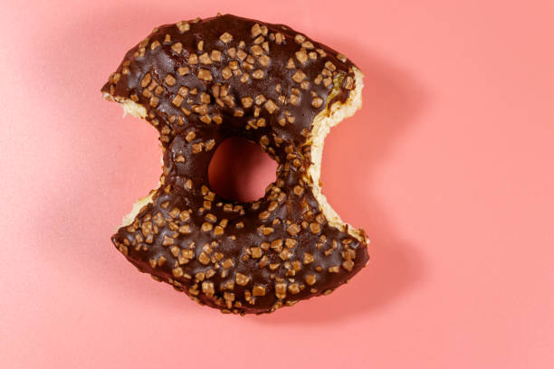 istock Bitten tasty chocolate donut on a pink background. Top view 1210192097