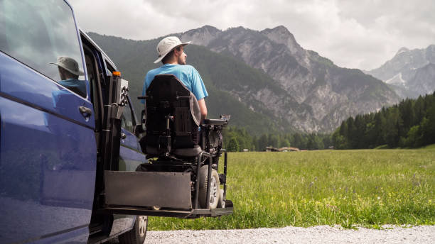 man on wheelchair going out of a car on electric lift specialized vehicle for people with disabilities. Self help for disabled people concept electric lift specialized vehicle for people with disabilities. Empty wheelchair on a ramp with nature and mountains in the back wheelchair lift stock pictures, royalty-free photos & images