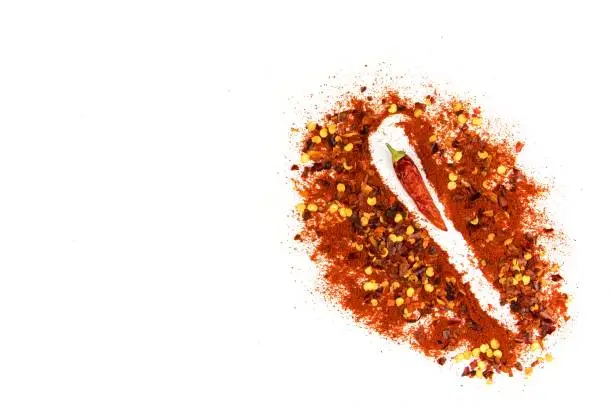 Hot spice. Chilli powder. Dried chili. Healthy spices. Spilled chili on white background.