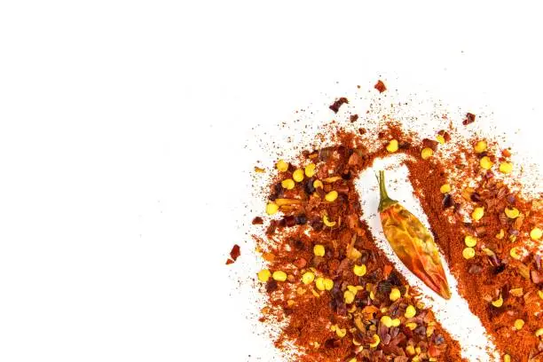 Hot spice. Chilli powder. Dried chili. Healthy spices. Spilled chili on white background.