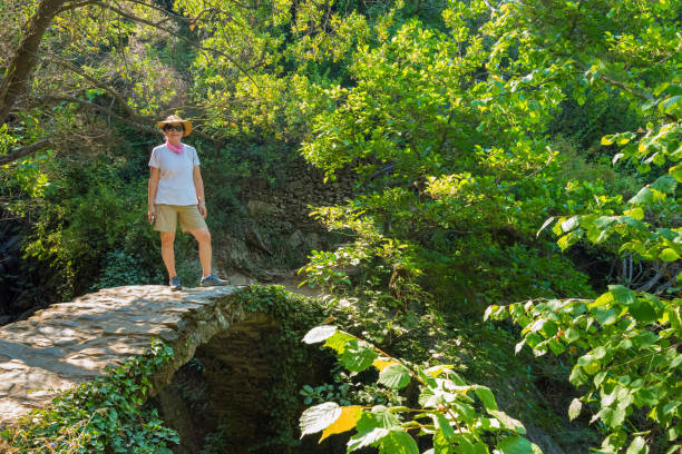 Mature Asian woman hiking trails through the mountain vineyards between Monterosso and Vernazza, Italy