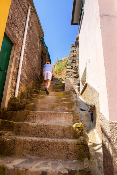 Mature woman climbing the steps of the old village of Vernazza, Italy. One of the Five towns of Cinque Terre.