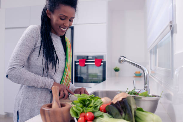 istock Happy woman preparing salad on the kitchen countertop. 1210195054