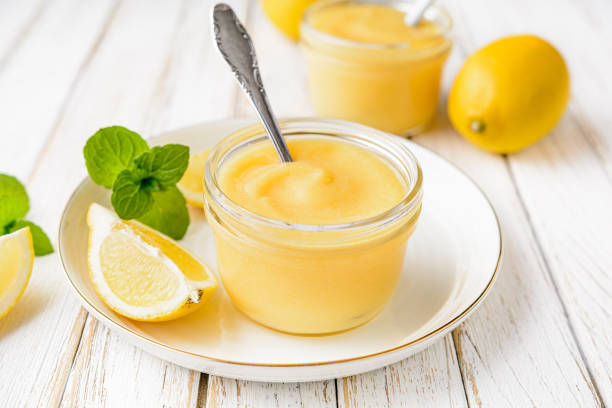 Homemade tangy lemon curd decorated with fresh fruit in a glass jars on rustic wooden background stock photo