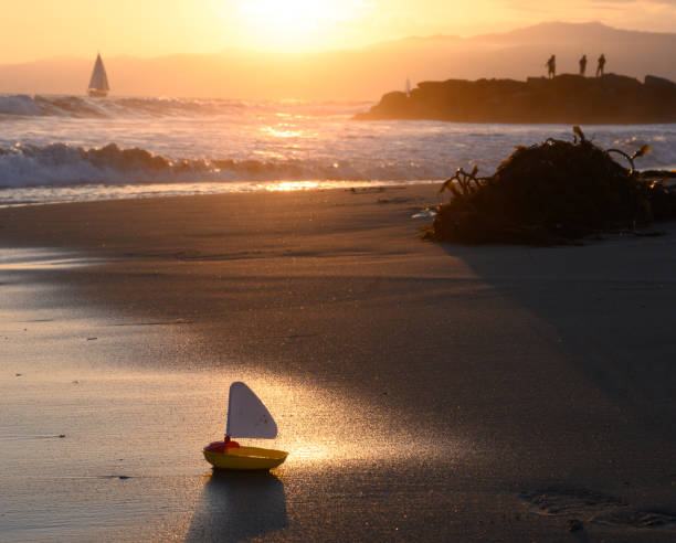 Toy boat on sand at sunset