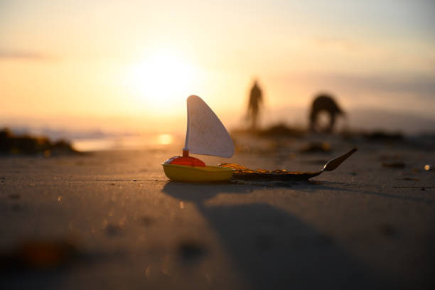 Children's toys with blue note showing copy space are laying on the sand of a sunny beach
