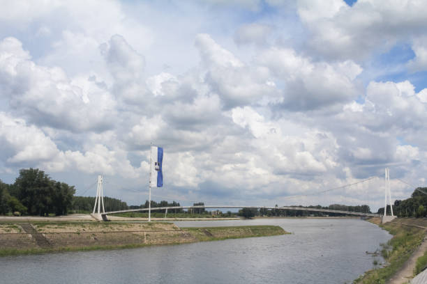 Youth bridge of Osijek, Croatia, also called Pedestrian bridge, or Most Mladosti, with the coat of arms of Osijek on a flag in foreground. It is a major landmark of the main city of Slavonia. Panorama of the Drava river in Osijek, croatia, with the flag of the city and the Most Mladosti bridge. Also called pedestrian bridge, or pjesacki most, it is a suspension bridge in Osijek, Croatia spanning the Drava River. It is one of the most notable symbols of Osijek. osijek photos stock pictures, royalty-free photos & images