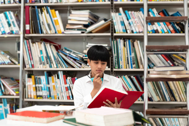 istock Young teenager searching data from book,with interested feeling,at library 1210220182