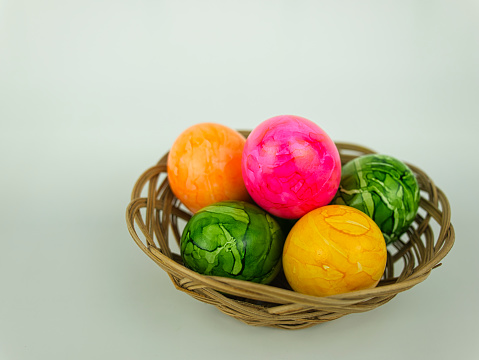 Five coloured Easter eggs in a small woven basket