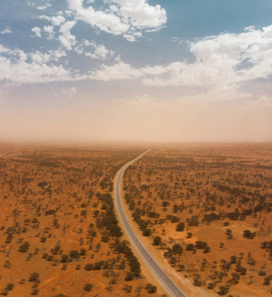 aereo drone di un'autostrada attraverso il vasto outback australiano con tempesta di polvere all'orizzonte - outback desert australia sky foto e immagini stock