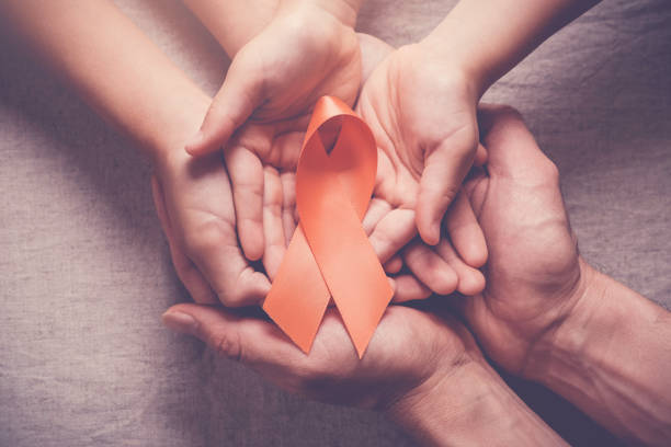 Adult and child hands holding orange Ribbons,  Leukemia cancer and Multiple sclerosis, COPD and ADHD awareness, world kidney day stock photo