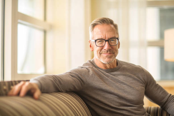 istock Portarit of a handsome older man sitting on a sofa. 1210235380