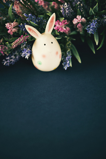 Dark blue Easter still life background with Easter egg bunny and flowers