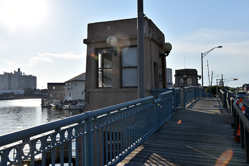 A boardwalk running along a drawbridge over a bay of water with natural lens flare