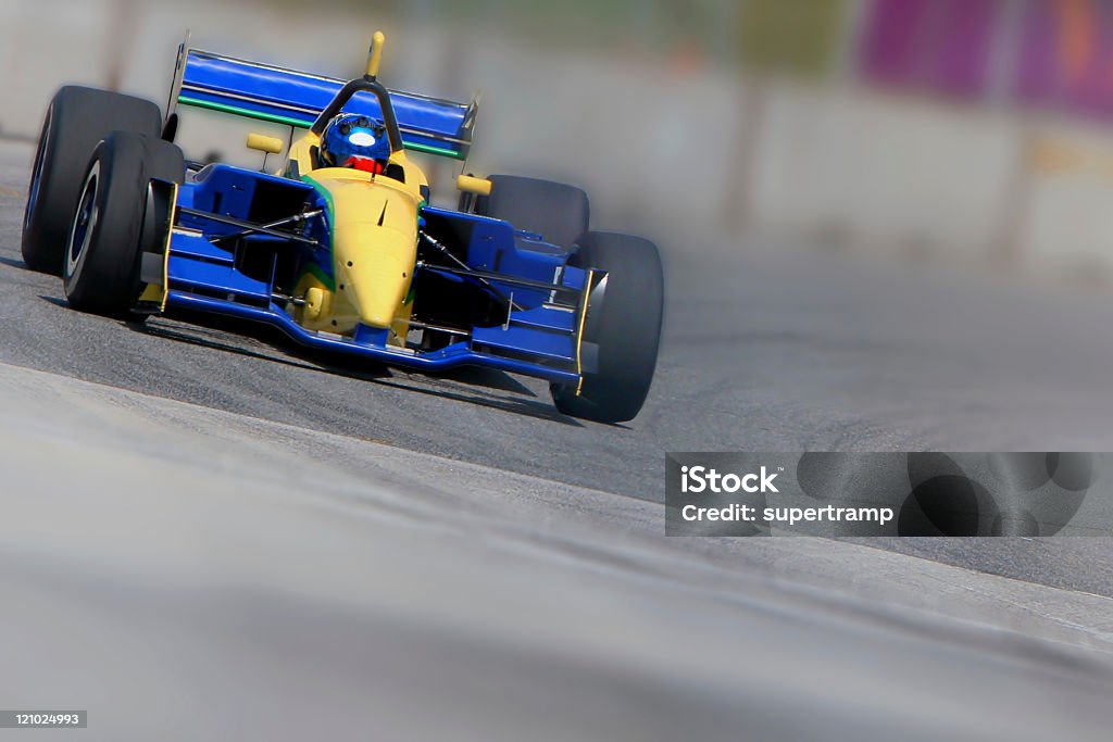 Blue and yellow racecar in motion on a racetrack Open wheeled single-seater race car in a corner with limited depth of field Racecar Stock Photo