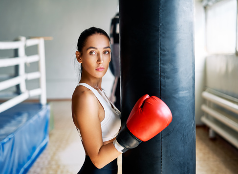 Sporty young woman wearing boxing gloves posing in gym. Sport concept