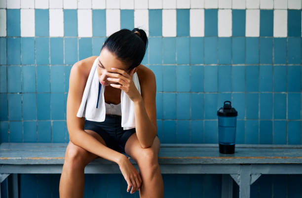 Tired fit woman with a towel in the locker room after hard workou stock photo