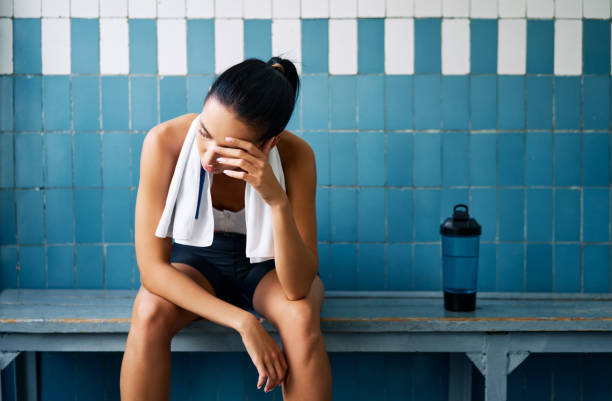 Tired fit woman with a towel in the locker room after hard workou Tired fit woman with a towel in the locker room after hard workout. Stress, sport, failure concept athlete fails stock pictures, royalty-free photos & images